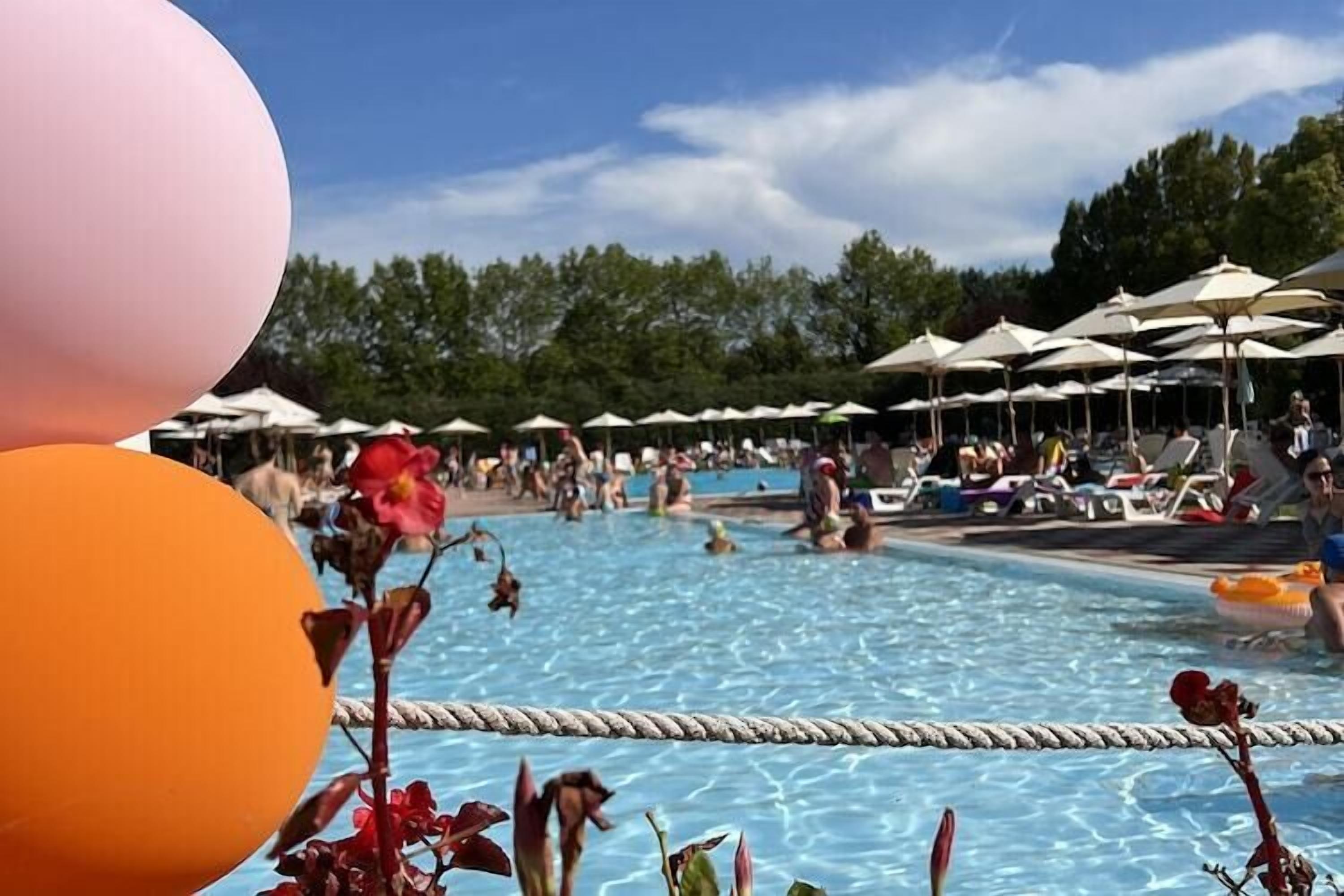 A swimming pool area with lounge chairs and umbrellas.