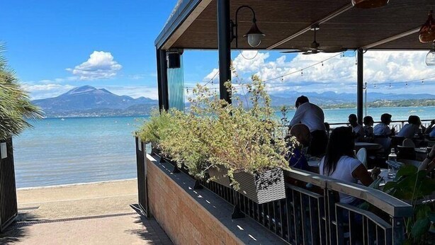 An outdoor dining area with a view of a lake and mountains.