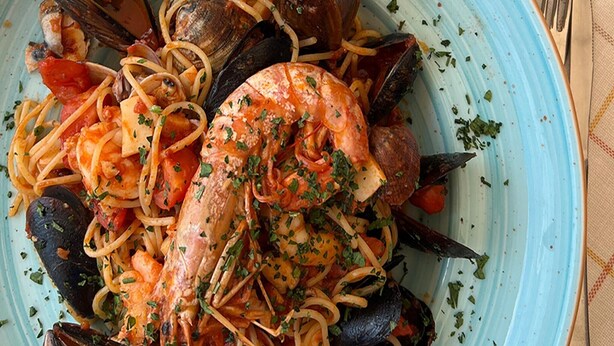 Een pastagerecht met zeevruchten, zoals mosselen, garnalen en kokkels, gepresenteerd op een bord.