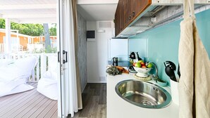 Een compacte keuken met een spoelbak, een raam en uitzicht op een terras en buitenruimte.