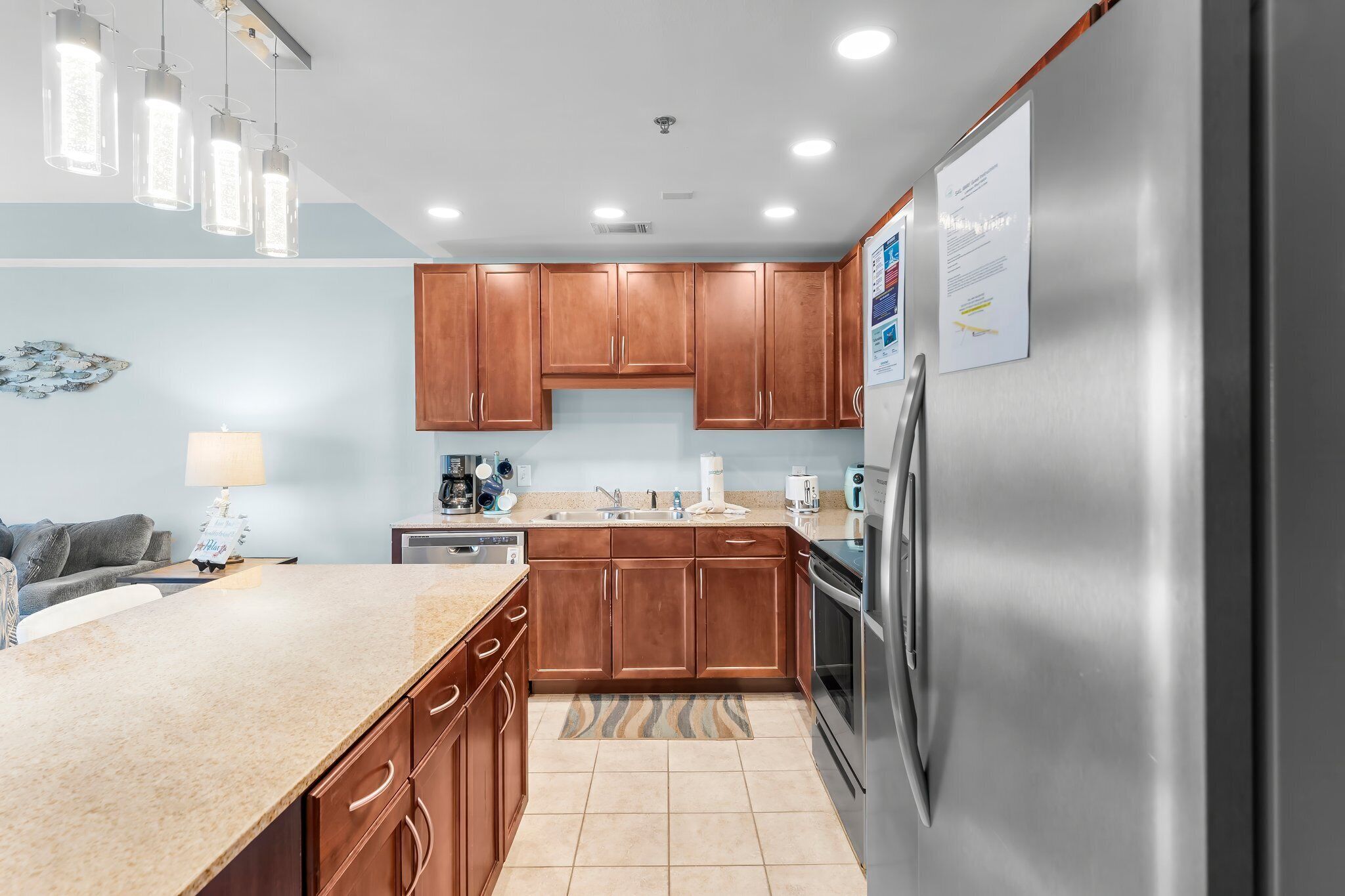 A modern kitchen with wooden cabinets, stainless steel appliances, and pendant lighting.