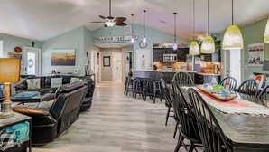 A spacious living area with a dining table, chairs, a sofa, and a ceiling fan. - Blue Heaven -  First Responders discount-  4 bedroom, 2 bath, sleeps 15. (Crystal Beach)