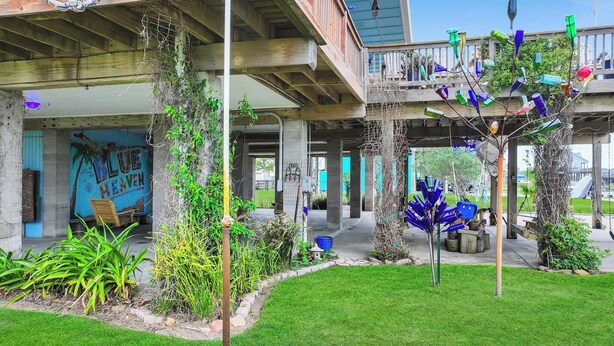 A covered outdoor area with a wooden deck, a mural, and various plants. - Blue Heaven -  First Responders discount-  4 bedroom, 2 bath, sleeps 15. (Crystal Beach)