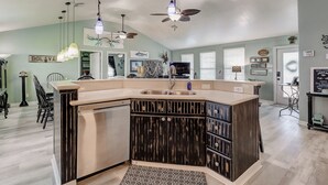 A kitchen with a central island, dark wooden cabinets, and pendant lighting. - Blue Heaven -  First Responders discount-  4 bedroom, 2 bath, sleeps 15. (Crystal Beach)