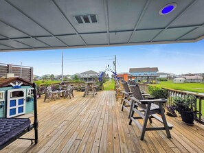 Une terrasse en bois avec des sièges d’extérieur, une petite maison de jeu et une vue sur les maisons au loin.