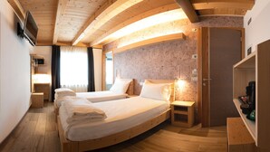 Une pièce chaleureuse avec deux lits, un plancher en bois, un grand miroir et un plafond en bois.