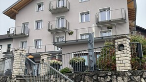 Un immeuble à plusieurs étages, doté de balcons, d’un escalier en pierre et d’un mur en pierre.