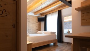 Ein Schlafzimmer mit einem hölzernen Bett, einem Kleiderschrank und einem Fenster mit Vorhängen.