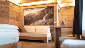Una habitación acogedora de madera con una cama, un sofá y una mesa con una copa de vino.