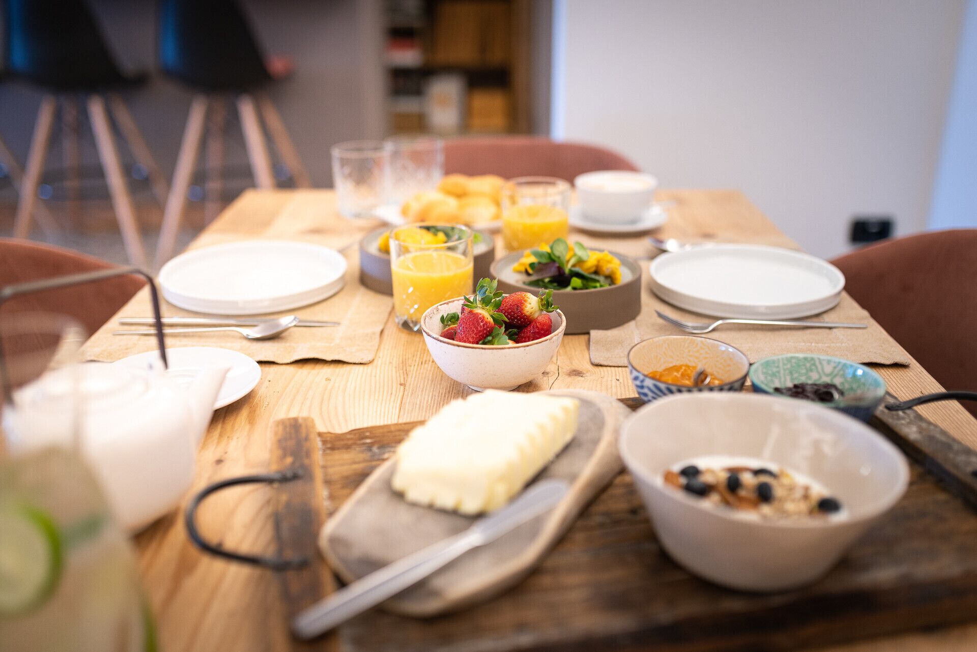 Une table de petit-déjeuner avec divers plats, notamment des fruits, du yaourt et des viennoiseries.