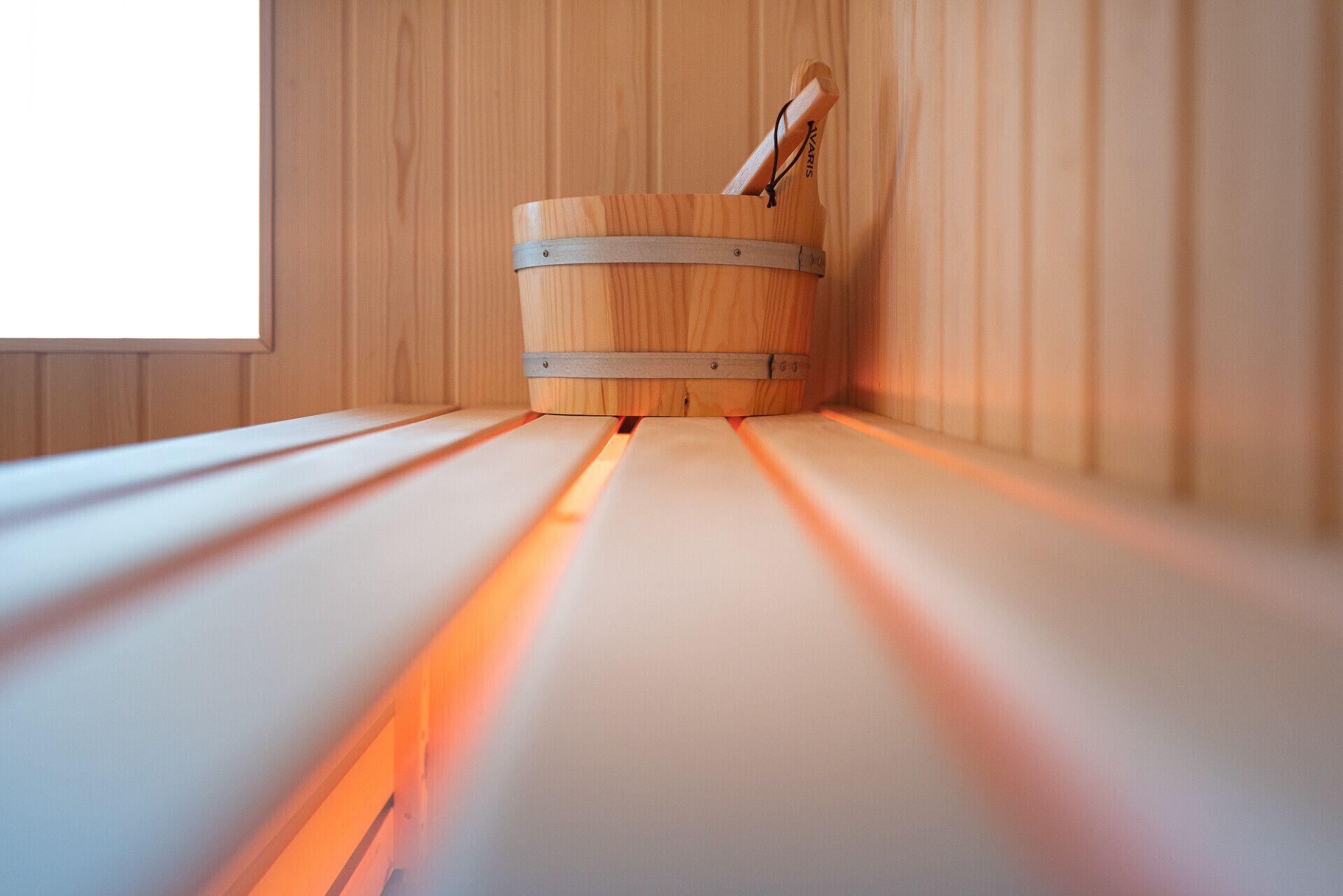 Una sauna con una panca di legno e un catino di metallo.