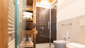 Un baño moderno con ducha acristalada, lavabo de madera y bidé.