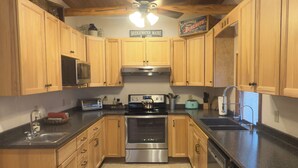 A kitchen with wooden cabinets, a microwave, a stove, and a ceiling fan. - Prime Snowmobile-Friendly Villa in Northern Maine  Winter Trails & Comfort (Bridgewater)