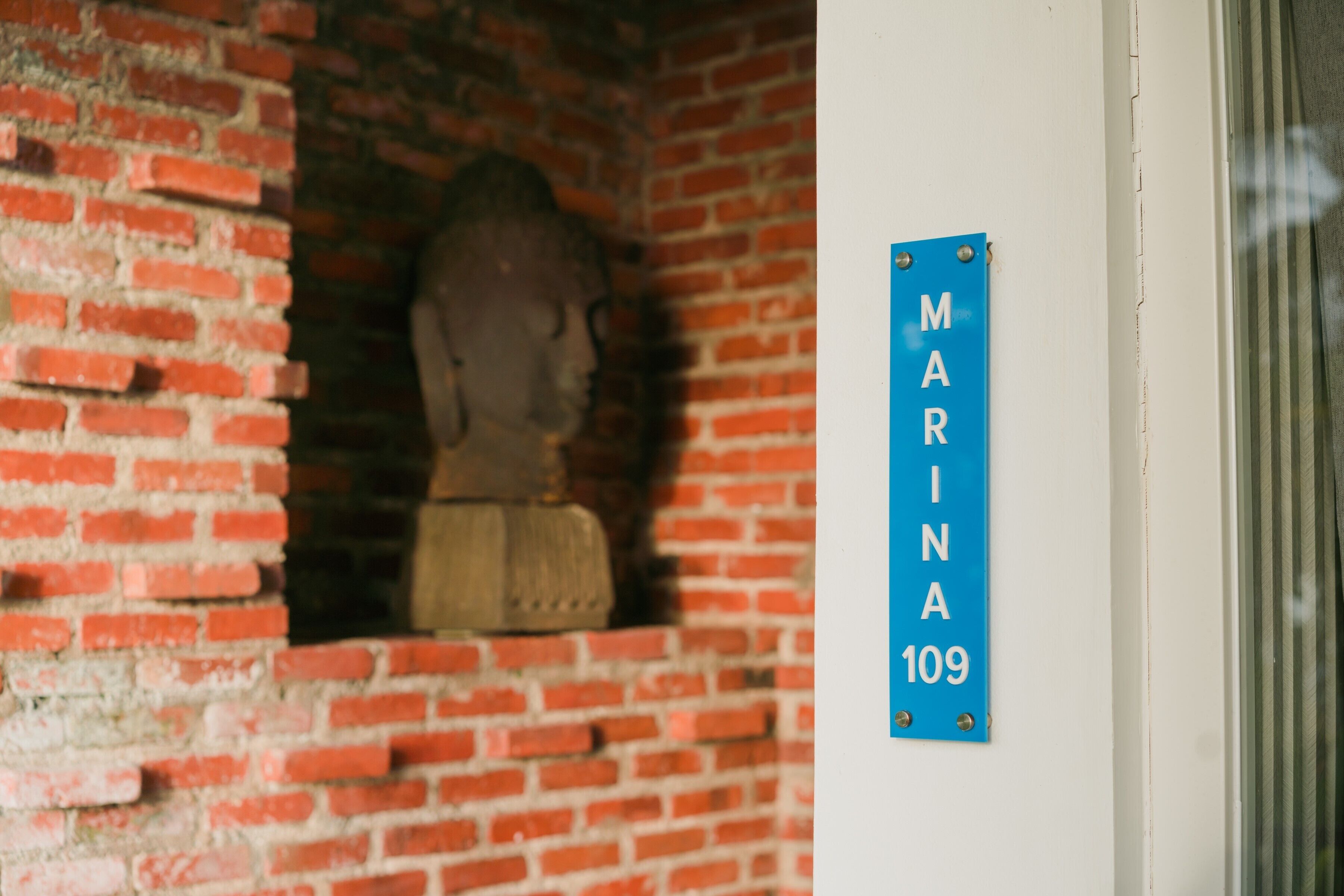Un muro de ladrillo con un letrero azul que dice "MARINA 109".