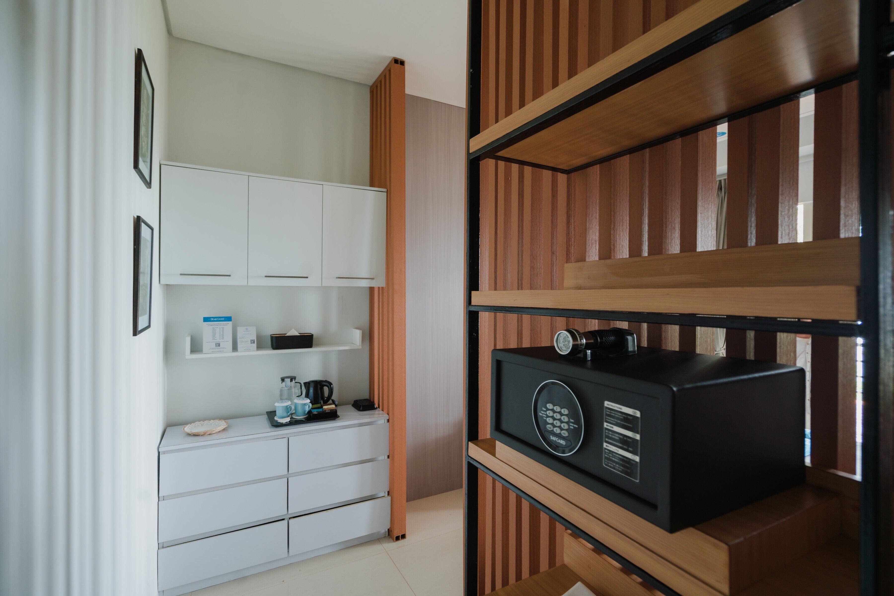 Una habitación moderna con armarios blancos, una cafetera y un altavoz negro sobre una estantería de madera.