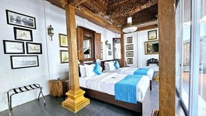 Una habitación con dos camas, vigas de madera, cuadros enmarcados en la pared y una pequeña mesa.