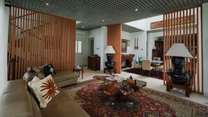 Amplia sala de estar con techo alto, alfombra grande y separadores de madera.