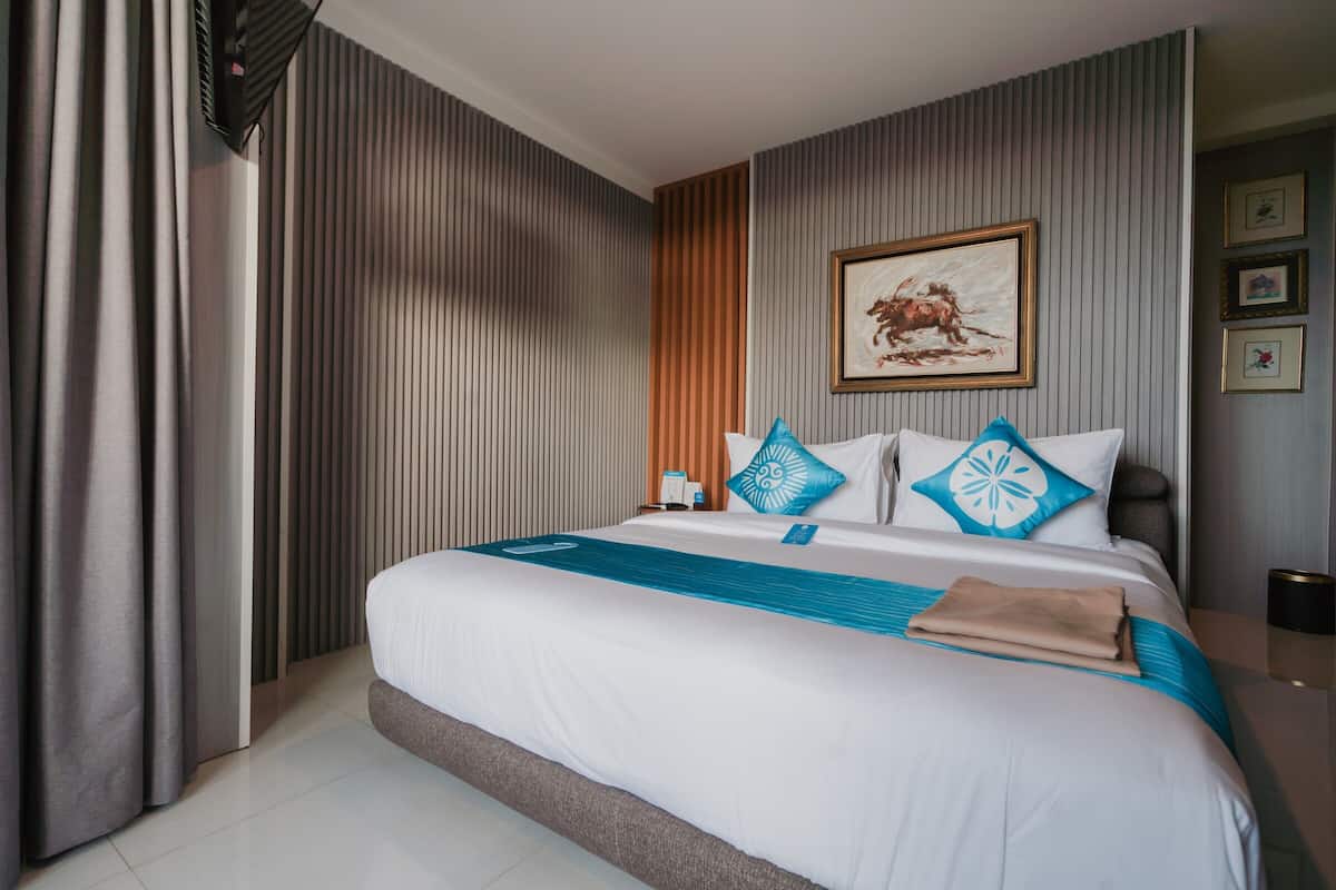Una habitación de hotel moderna con una cama grande, un cuadro en la pared y vistas a la ciudad.