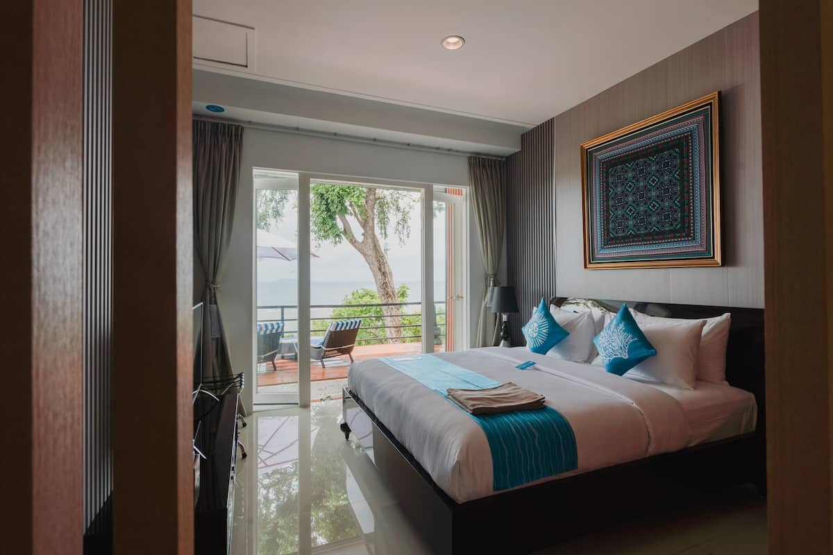 Una habitación de hotel moderna con una cama grande, un balcón con vistas y un elemento decorativo en la pared.