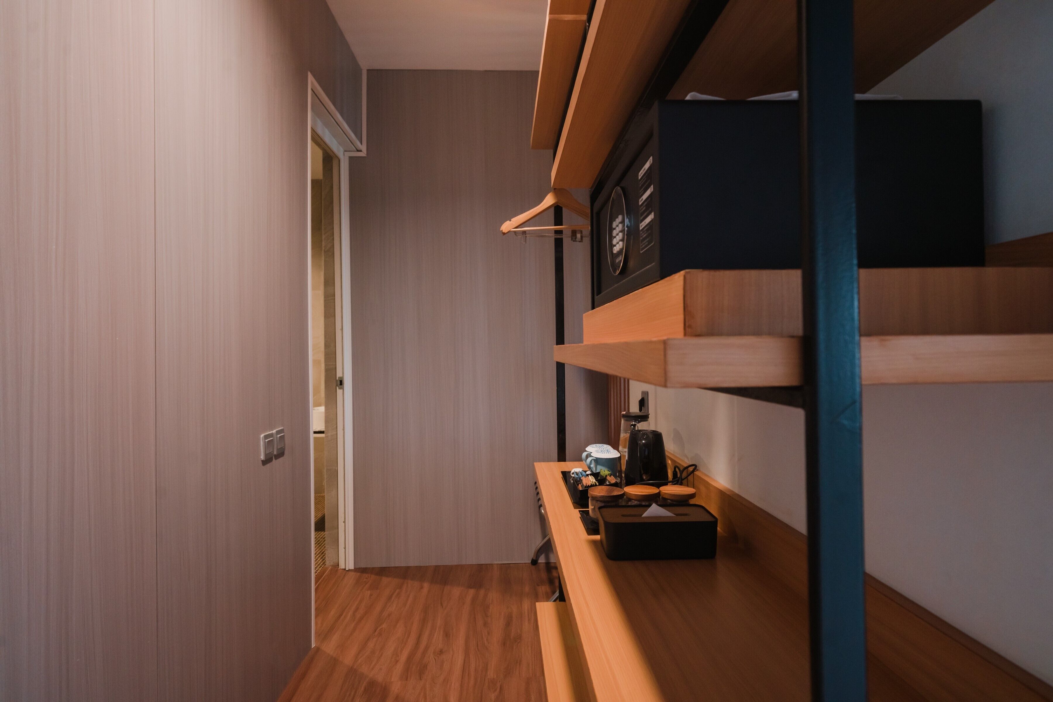 Un pasillo estrecho con un banco de madera y una pequeña mesa con una tetera y tazas.