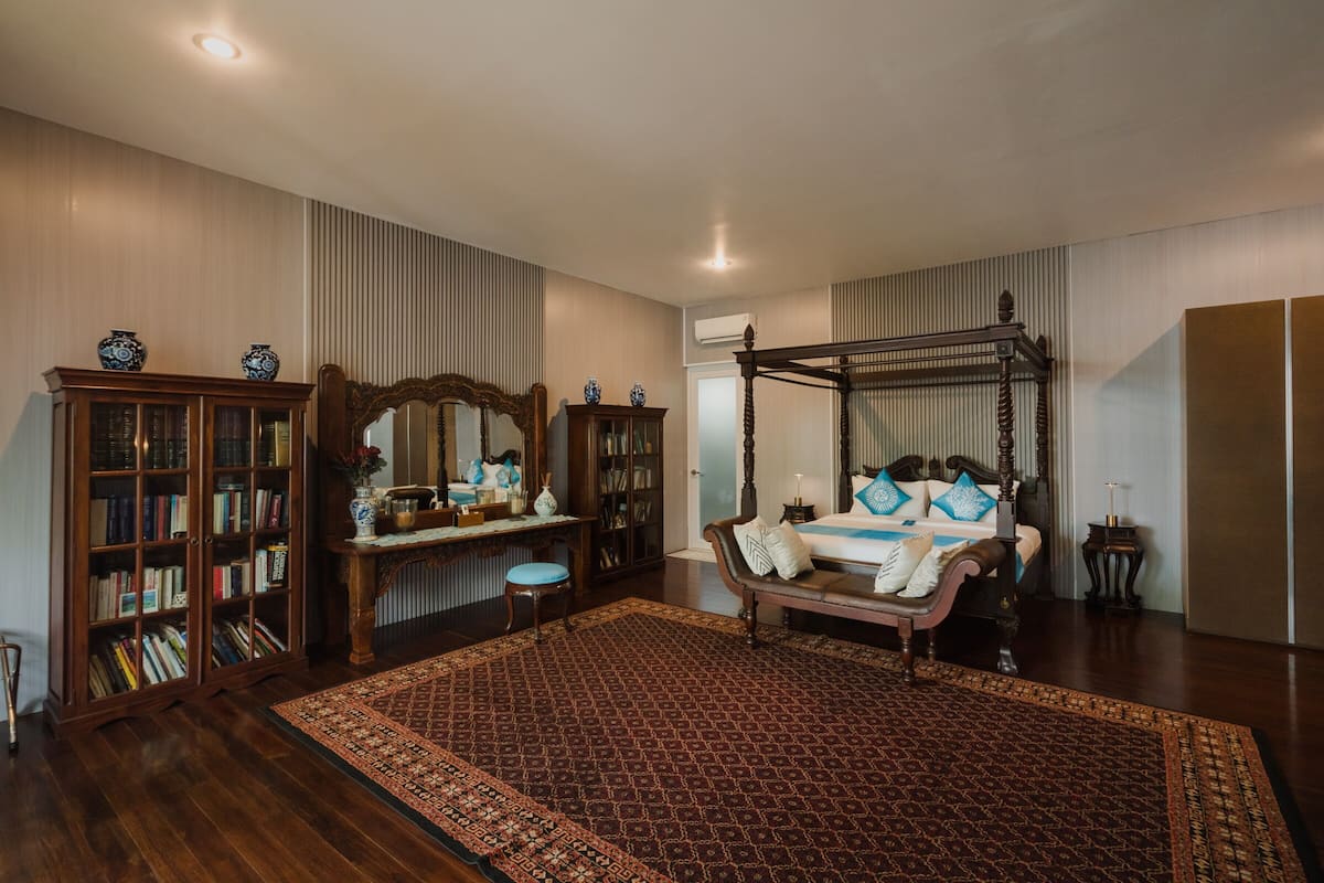 Un dormitorio con una cama con dosel, una amplia estantería de madera y un espejo decorativo.