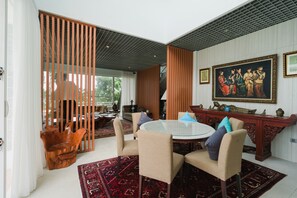 Un comedor con una mesa redonda, sillas y una silla de madera decorativa.
