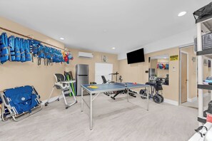 Een kamer met een tafeltennistafel, fitnessapparatuur en een rolstoel.