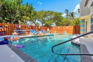 Une piscine avec des chaises longues et une clôture en bois.