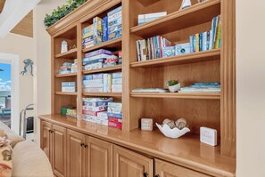 A wooden bookshelf filled with books and games, a small potted plant, and a 'NO WAKE ZONE' sign.