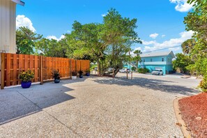 A residential street with a wooden fence, potted plants, and a blue house in the background. - Aquarius Ocean-to-River Resort: 26BR/18BA Beachfront, Sleeps 60+ Pools/Spa/Docks (Stuart)