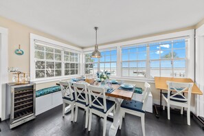 Une cuisine lumineuse avec des meubles blancs, un réfrigérateur à vin intégré et une grande fenêtre donnant sur un paysage magnifique.