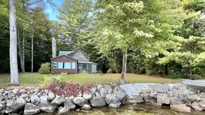 A house with a stone wall and a pond in front. - LARGE RUSTIC COTTAGE WITH BUNK HOUSE.  SLEEPS 17.  (Sebago)
