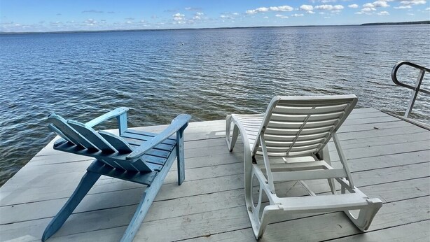 A wooden pier with two lounge chairs facing a calm body of water under a partly cloudy sky. - LARGE RUSTIC COTTAGE WITH BUNK HOUSE.  SLEEPS 17.  (Sebago)