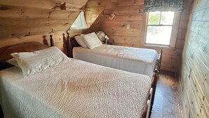 A cabin with two wooden beds, a window, and a ceiling light. - LARGE RUSTIC COTTAGE WITH BUNK HOUSE.  SLEEPS 17.  (Sebago)