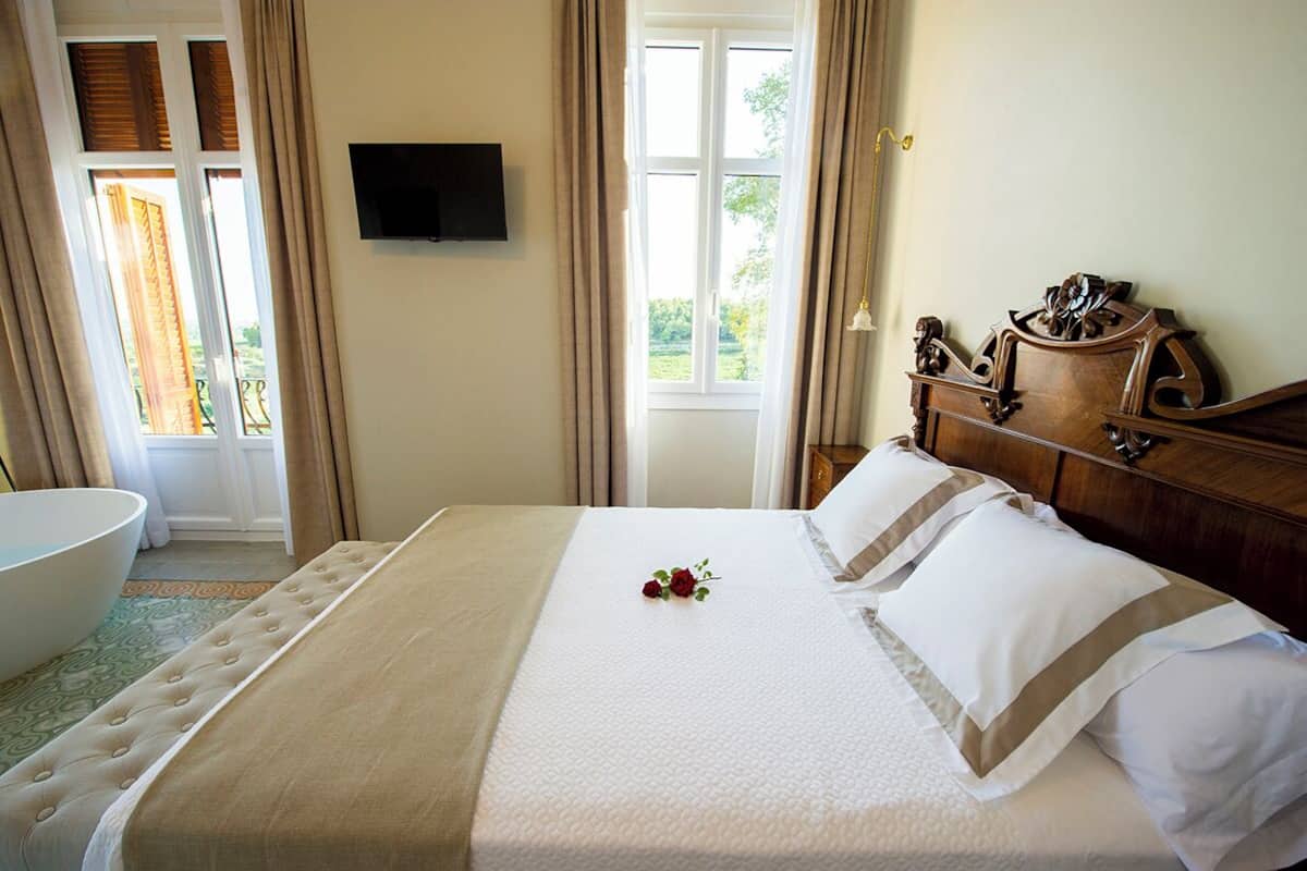 Una habitación de hotel con una cama grande, un aparador de madera, un televisor en la pared y una bañera.