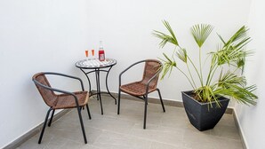 A small outdoor seating area with two wicker chairs and a round table, a potted plant, and a bottle of red drink. - Bolet Casa Modernista (Castellvi de la Marca)