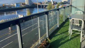 Ein Balkon mit Blick auf einen Fluss, eine Brücke und moderne Gebäude.
