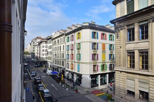 Vista de una calle en una ciudad europea con edificios de colores, coches aparcados y peatones.