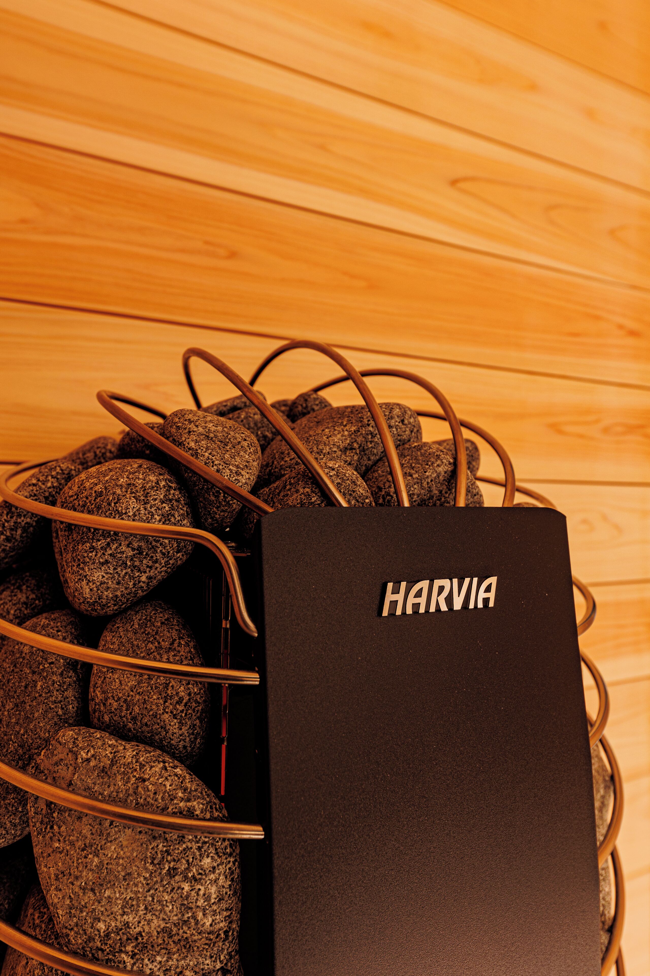 A black Harvia bag with a metal wire basket containing rocks.