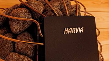 A black Harvia bag with a metal wire basket containing rocks.