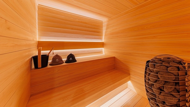 Een houten sauna met banken, een emmer en een houtrek.