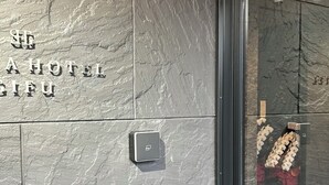Een met structuur afgewerkte muur met een bord voor 'Hotel A' en een deur met een ruit.