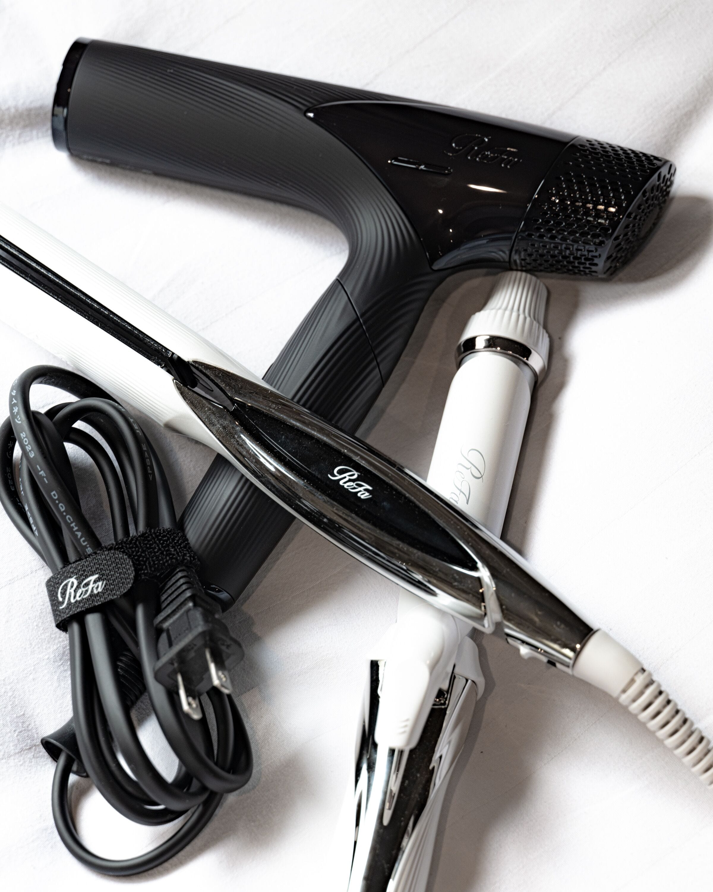A hair dryer and a curling iron with a power cord.
