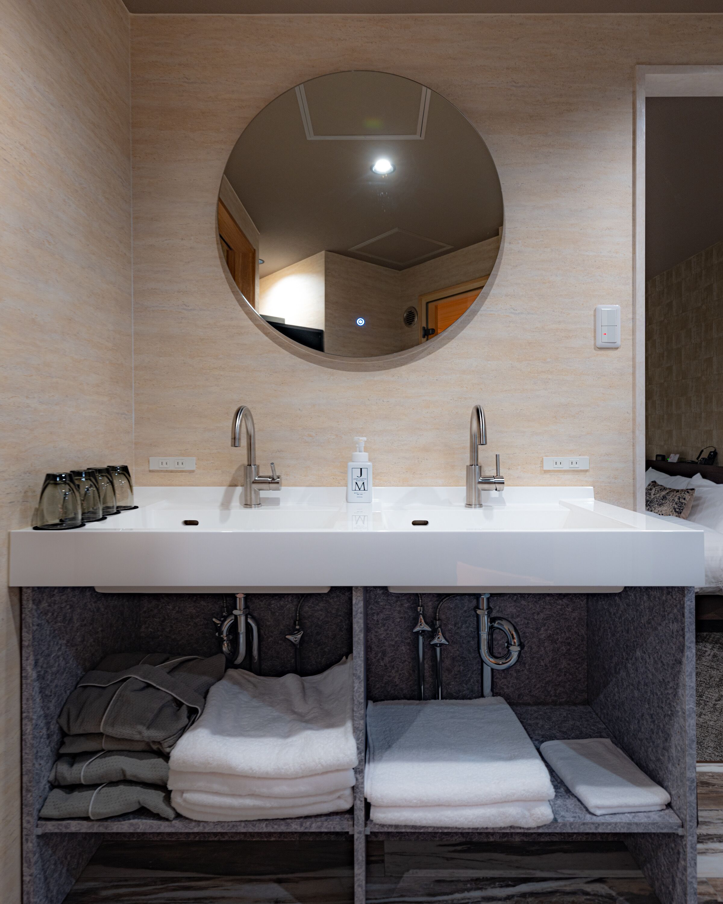 Une salle de bain moderne avec un grand miroir, deux lavabos et un porte-serviettes où sont pliées des serviettes.