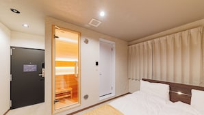 Een hotelkamer met een bed, een houten deur, een badkamer en een douche.