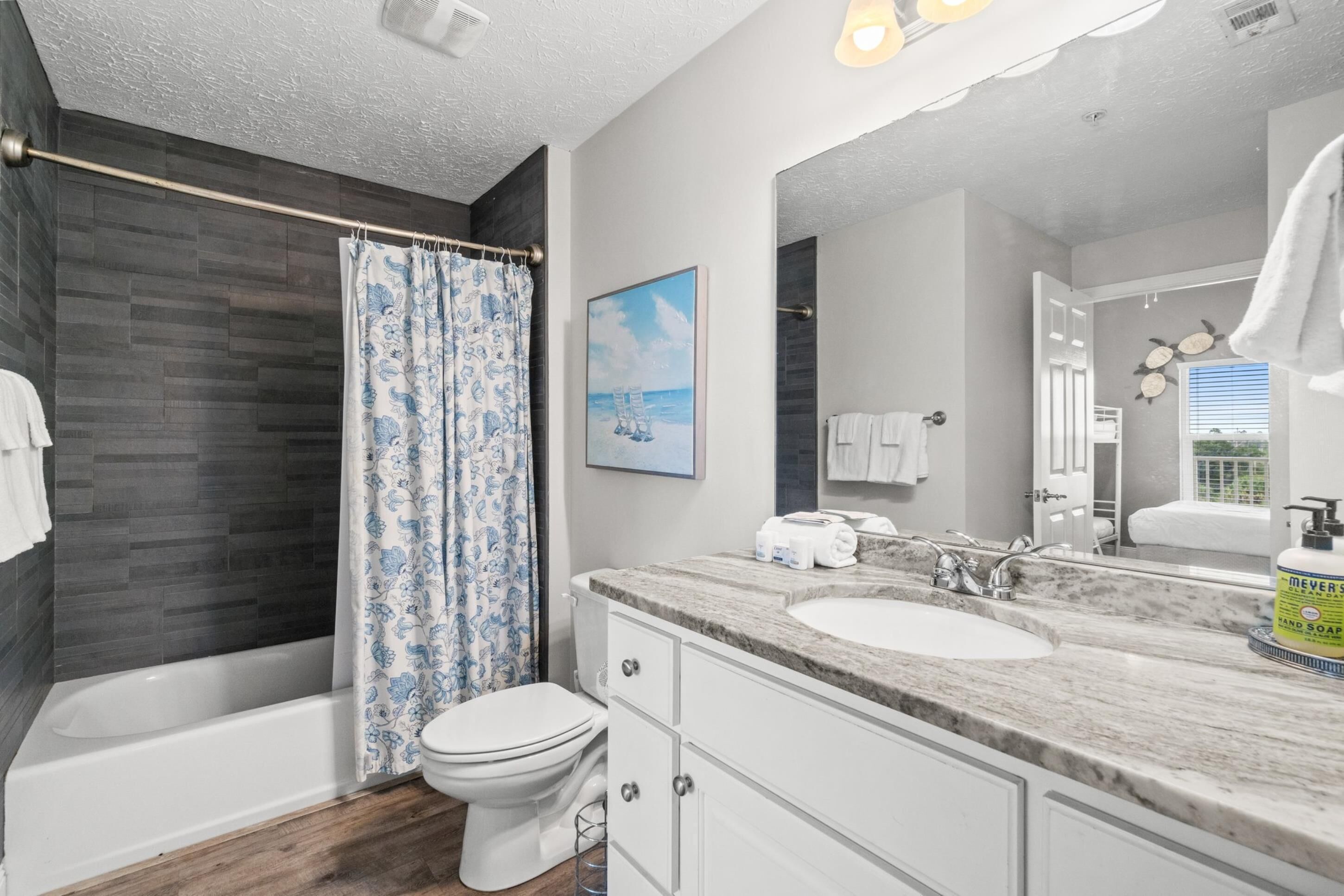 A modern bathroom with a bathtub, toilet, and a large vanity with a sink and mirror.
