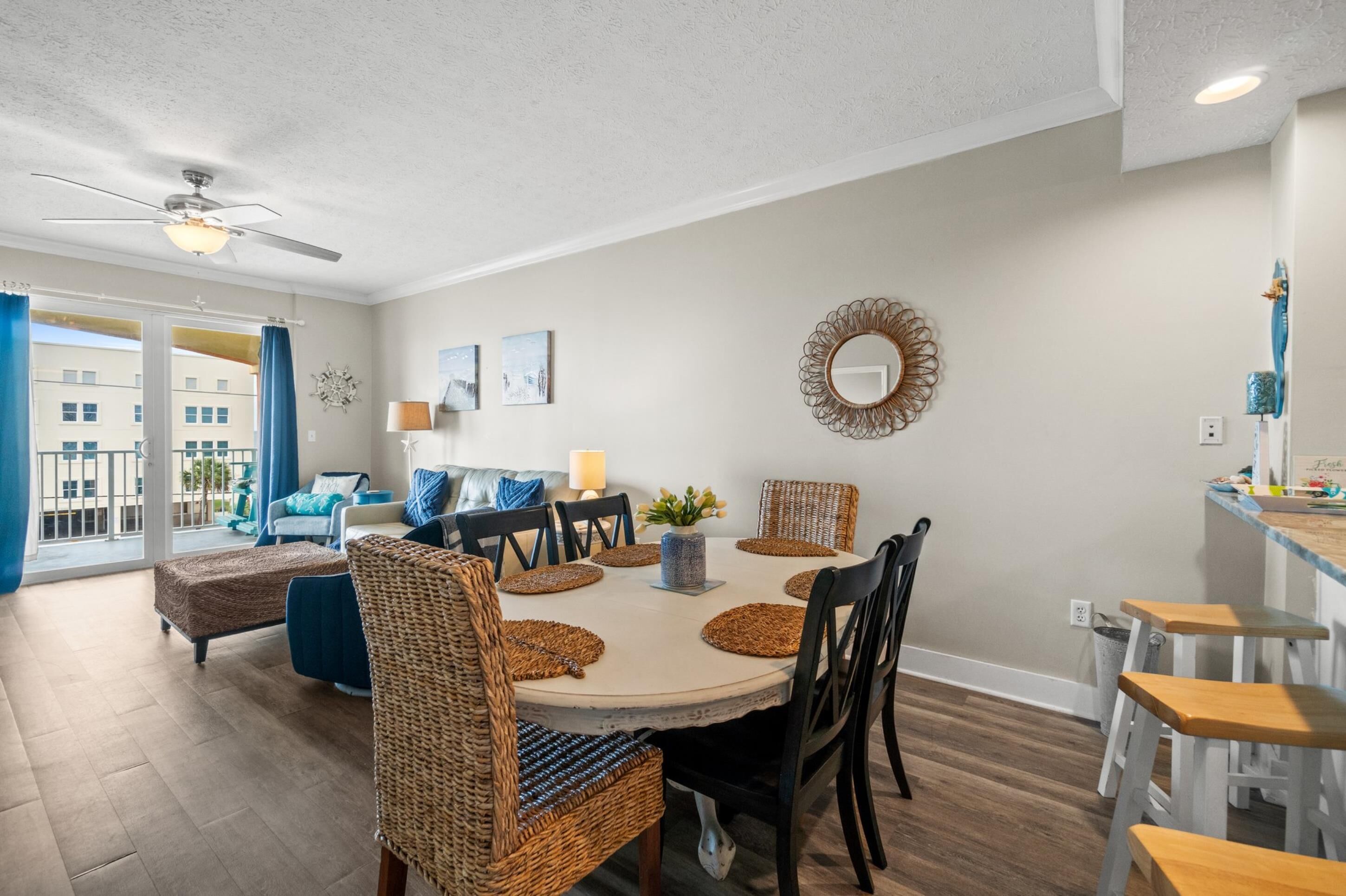 A dining area with a round table, wicker chairs, and a ceiling fan.