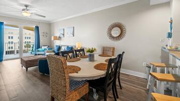 A dining area with a round table, wicker chairs, and a ceiling fan.