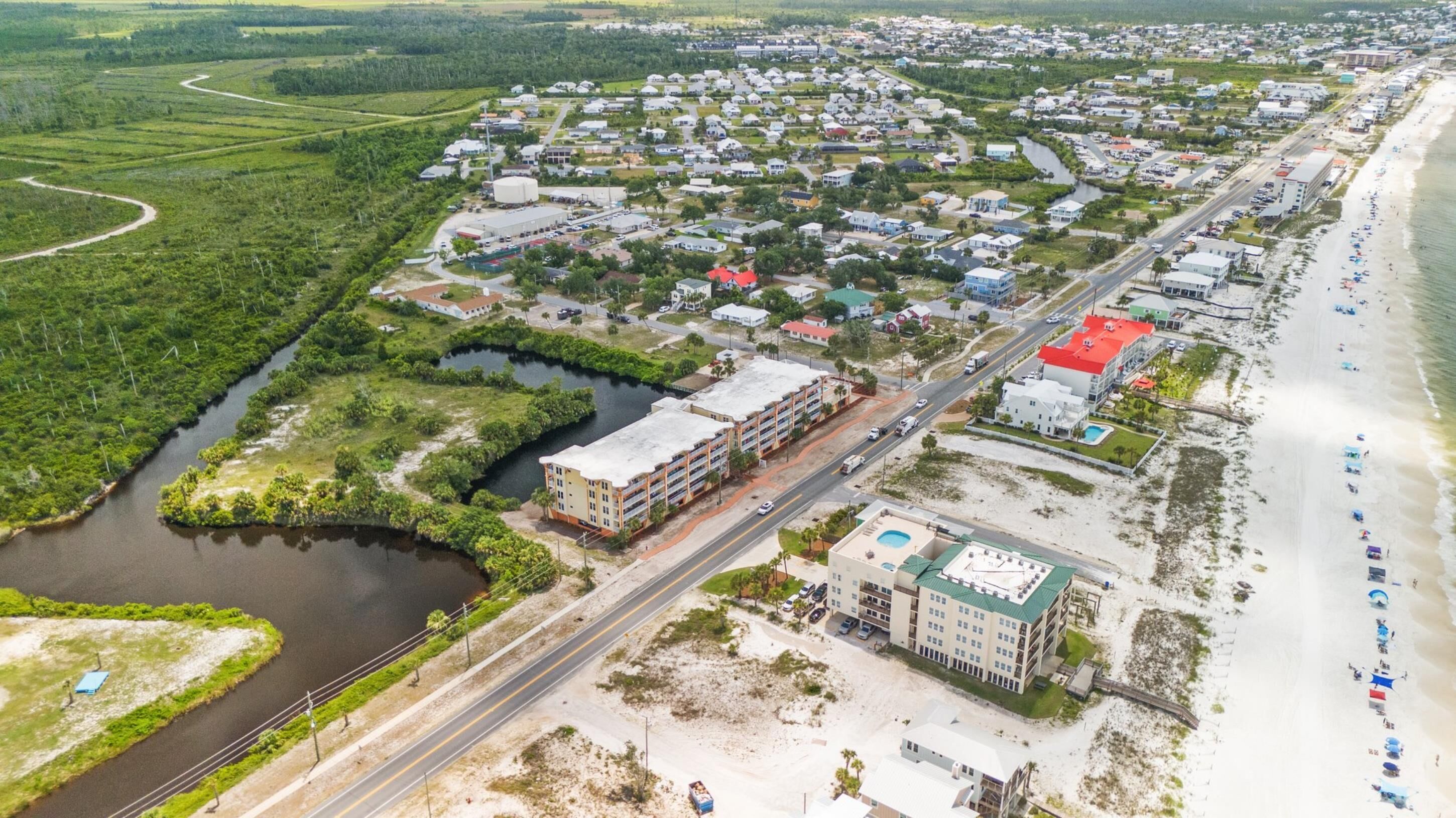 Vista aérea de un pueblo costero con playa, río y una combinación de edificios residenciales y comerciales.