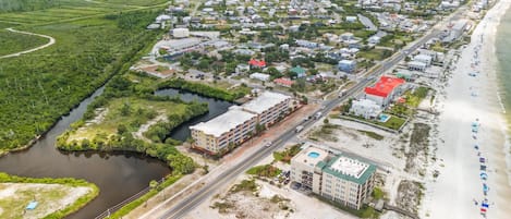 Vista aérea de un pueblo costero con playa, río y una combinación de edificios residenciales y comerciales.